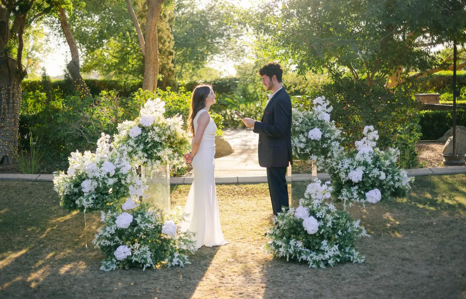Couple exchanging vows between white rose arrangements