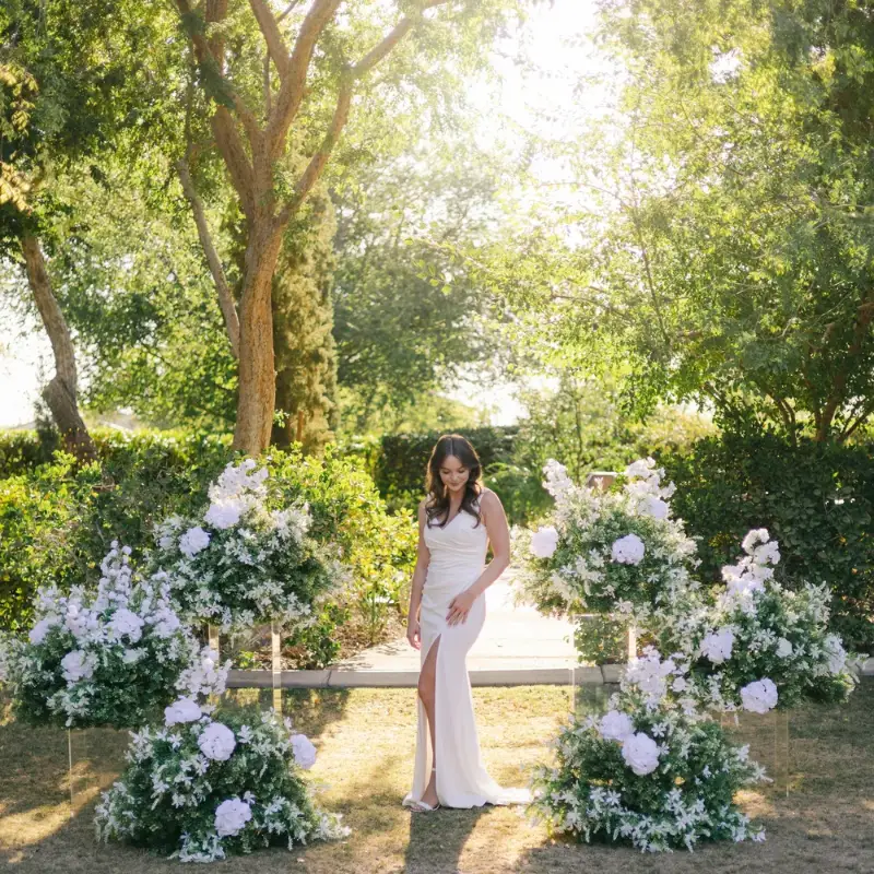Bride standing between white floral pedestal arrangements